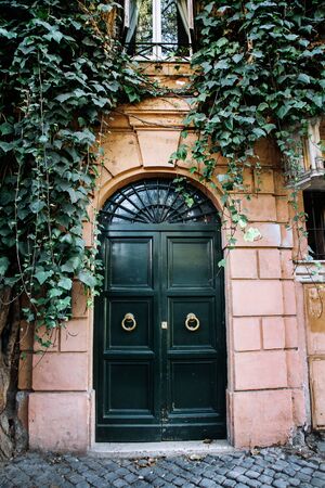 The entrance wooden door covered with green ivy. Rome, Italy.の写真素材