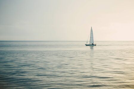Sailing boat on open sea at sunset.の写真素材