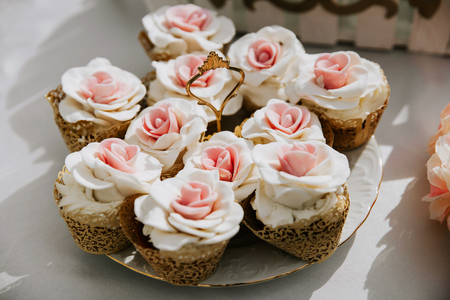 Cupcakes decorated with pink flowers, served on a banquet table.の写真素材