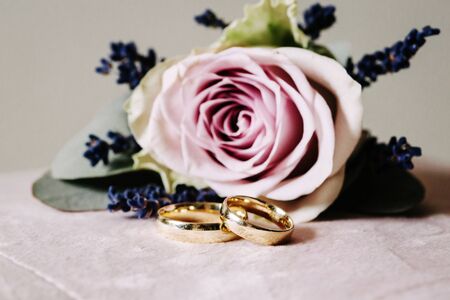 Two golden wedding rings and bouquet of flowers.の写真素材