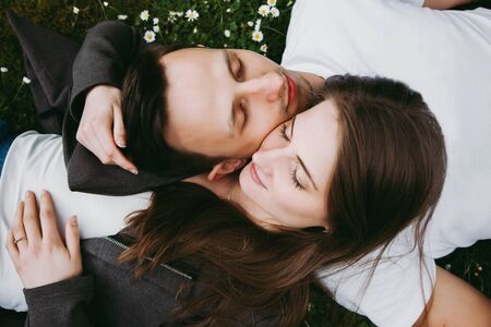 Young loving couple outdoors lying on grass, eyes closed, top down view.の写真素材