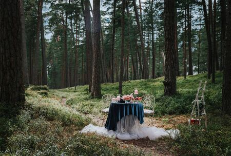 Romantic table setting with flowers and candles in the forest.の写真素材