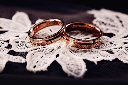 Two golden wedding rings arranged on the white lace flower.の写真素材