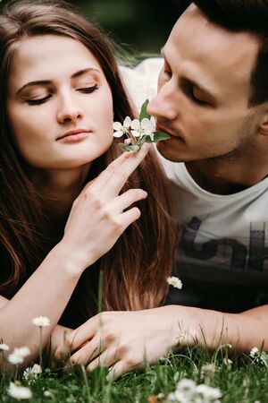 Young loving couple outdoors sitting on grass, hugging.