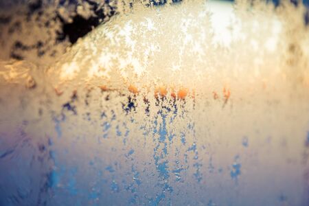 View through a frosting window. Ice flowers macro. Winter and Christmas background.