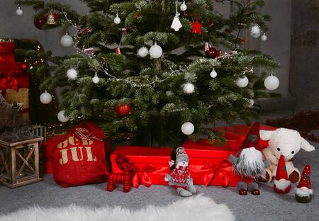 Decorated Christmas tree with presents arranged under the tree. Close up image of three small dwarfs.の写真素材