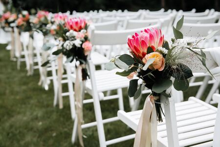 Decorated luxury wedding ceremony place in the garden. White empty chairs decorated with flowers.の写真素材