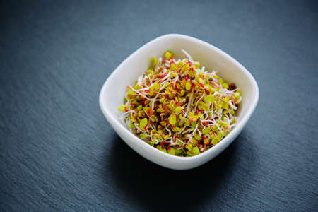 Fresh radish sprouts in a shape of heart, isolated on black background. Concept for a healthy eating. Top view.の写真素材