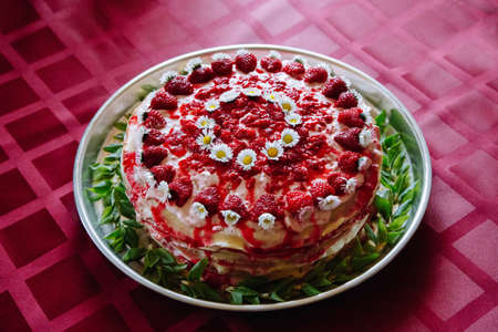 Delicious homemade cake decorated with raspberries, flowers and green leaves.の写真素材