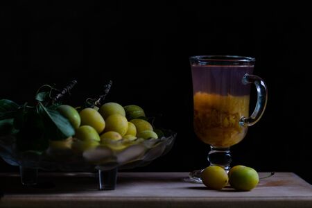 Still life with fresh yellow plums and glass of home made plum limonade, backlight, black backgroundの写真素材