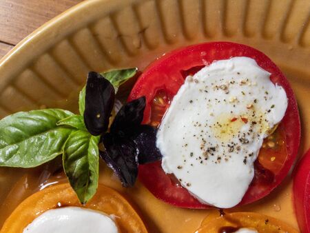 Sliced red and orange tomatoes with mozzarella, olive oil, basilの写真素材