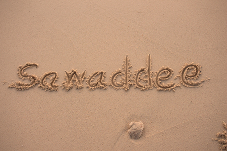 words  sawaddee written in the sand with fingerの写真素材