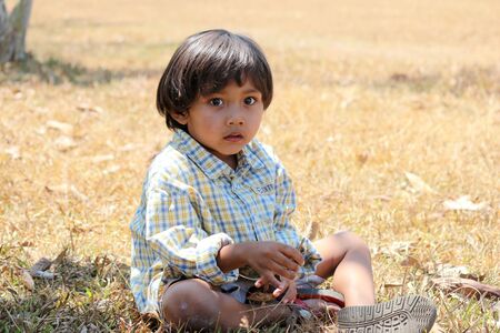 Boy sitting in the grass at summer.の写真素材
