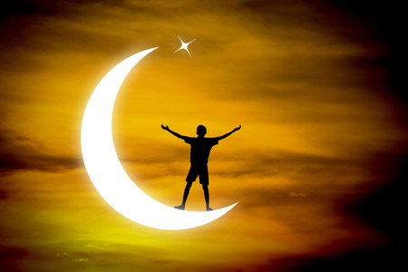 boy praying  on a moon at night.の写真素材