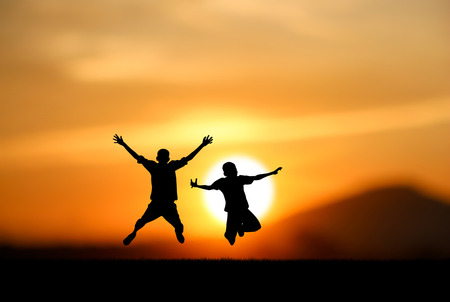 silhouette of boys jumping with joy at sunsetの写真素材