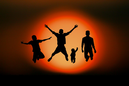 silhouette of father and boys jumping with joy at sunsetの写真素材