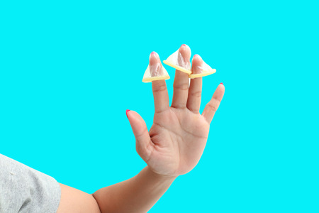 Red nail of woman hand with condom isolated on blue,safe sex concept. の写真素材
