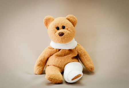 Teddy bear with bandage on gray background.の写真素材