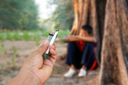 Hand give cigarette to sad boy,the concept of drug problems in youth.の写真素材