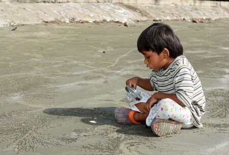 Joyful young boy examines a magnifying glass seashell on the beach summer seaの写真素材