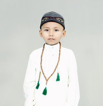 Portrait of muslim little cute kid with hat on gray background.の写真素材