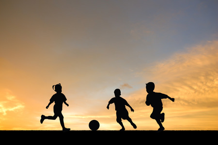 Many children were playing soccer at sunset.の写真素材