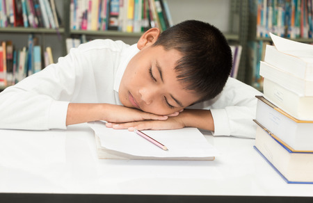Asian boy sleeping with his homework at the library.の写真素材