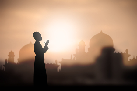 A silhouette of islamic praying at sunset.の写真素材