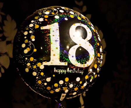 Balloon with number '18' and happy birthday's wishes in black backgroundの写真素材