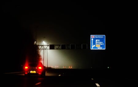 Cars moving through the highwaysCar moving through the highways in Netherlands in a foggy nightの写真素材