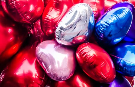 A bunch of heart shaped balloons in red, blue, pink silver and purple