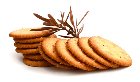 A stack of delicious wheat round biscuits with a few crumbs isolated on whiteの写真素材