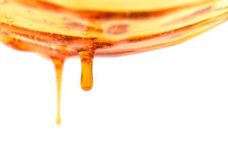 honey pouring into bowl isolated on white backgroundの写真素材