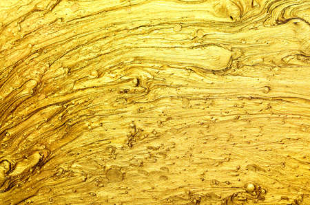 Abstract brush strokes with gold paint on paper.