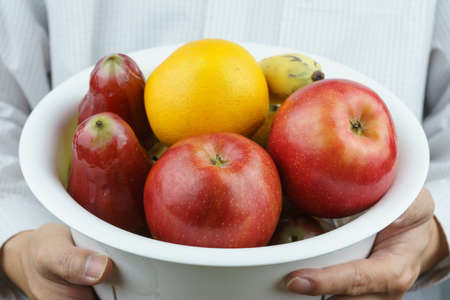 Male holding a basket in front of him that contained a variety of fruits. It is a vegetarian and...