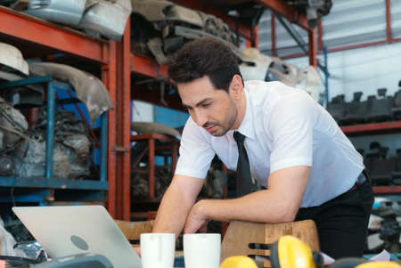 Caucasian business manager stand to work seriously with laptop-notebook in factory-warehouse