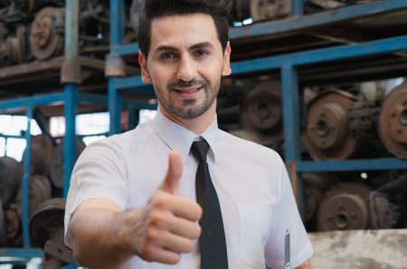 Caucasian business manager stand, smile, holding report, and give thumbs up to team well in factory-warehouseの写真素材