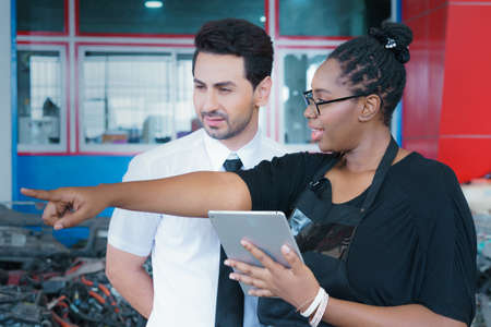 Diversity of two people, black African worker woman explain detail of product on a tablet to...