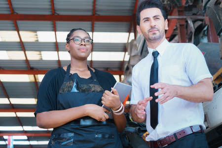 Diversity of two people, caucasian business manager and African worker woman looking to outside factory-warehouseの写真素材
