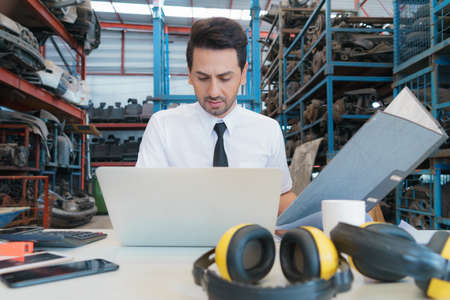 Caucasian business manager sitting, holding file, and work seriously with laptop-notebook in...
