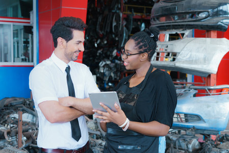 Diversity of two people, caucasian business manager smiling with black African worker woman who holding tablet in factory-warehouseの写真素材