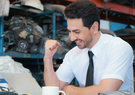 Caucasian business manager sitting with happiness successful in front of the laptop-notebook in factory-warehouseの写真素材