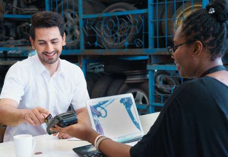 Man paid by credit card. Diversity of two people, caucasian business manager work with African worker woman in factory-warehouseの写真素材
