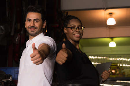 Man work with woman, they happy and give thumbs up. Diversity of two people, caucasian business manager and African worker woman happiness and give thumbs up in factory-warehouseの写真素材