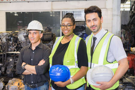 Men and woman work together, holding helmets and looking straight. Caucasian engineer manager men...