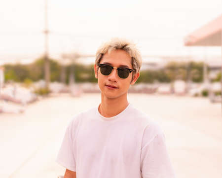 Half body of Asian handsome skater man wear sunglasses and act smart with copy space in daylight...