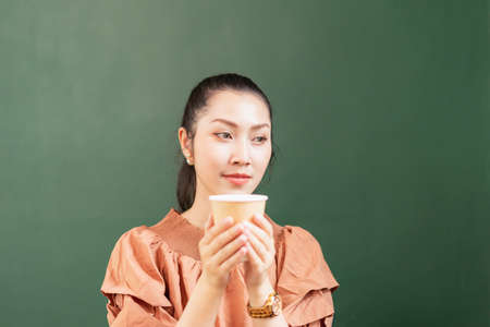 Right side of beautiful Asian woman customer sits blankly while drinking coffee in coffee shop. Barista work at coffee bar and food service businessの写真素材