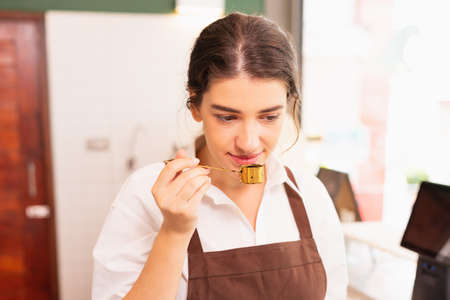 Beautiful caucasian barista woman tests coffee smell after grinding at coffee bar. Barista work at coffee bar and food service businessの写真素材