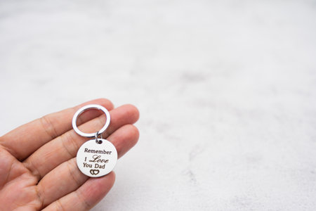 Scene of kid holds love keychain gift for father on father's day with stone background.