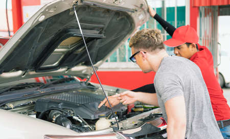 White caucasian car owner looking at main auto car engine after filling high energy power fuel in...